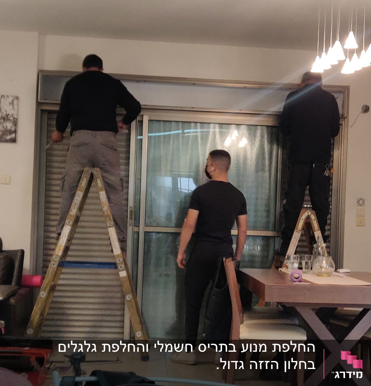 שני אנשים מתקנים תריסים על סולמות בחדר